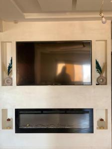 Appart haut standing في أغادير: تلفزيون بشاشة مسطحة فوق موقد في غرفة المعيشة