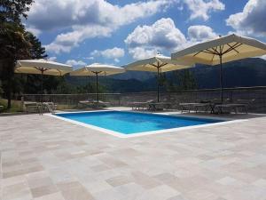 una piscina con sombrillas, mesas y sillas en Modern Holiday Home in Pelago with Pool en Donnini