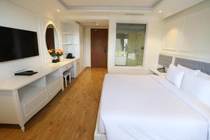 a bedroom with a white bed and a desk and a television at Nature Hotel - Pham Hong Thai in Da Lat