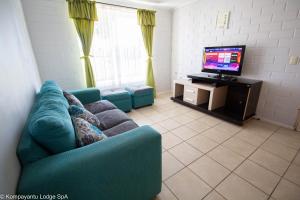 ein Wohnzimmer mit einem blauen Sofa und einem TV in der Unterkunft Kompayantu Lodge Arriendo Diario in La Serena