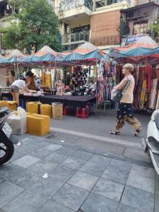 a woman walking past an outdoor market with tents at H2Homestay phố cổ check in tự động in Hanoi