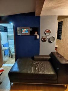 sala de estar con sofá de cuero y pared azul en Departamento de huéspedes Grijalva, en Ciudad de México