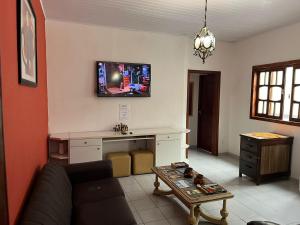 a living room with a couch and a tv on the wall at Hostel Alto do Rosario in Vitória