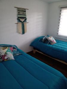 two beds in a room with blue sheets at Cabañas Del Valle in Curacautín