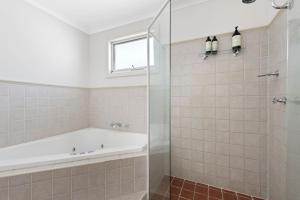 a bathroom with a tub and a glass shower at Beachwood House at Mollymook Beach in Mollymook +16 photos