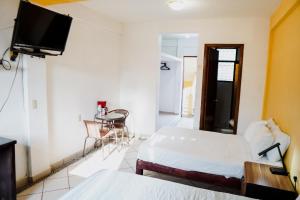 a bedroom with two beds and a tv on the wall at HOTEL ROBLE ZIHUATANEJO in Zihuatanejo