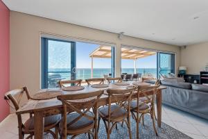 a dining room with a table and chairs with a view of the ocean at Aqua Shores Penthouse in Mollymook