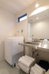 a white bathroom with a sink and a mirror at Social Guest House neltoko in Nanao