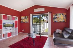 a living room with red walls and a black leather couch at Kokomo on Village in Ulladulla