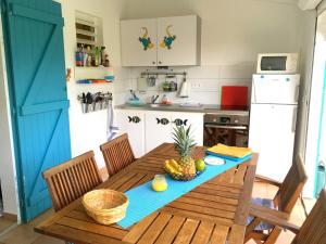 una cucina con tavolo in legno e ciotola di frutta di Bungalow La Papaye Bleue Résidence accès Piscine & Plage a Saint-François