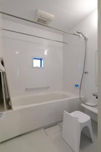 a white bathroom with a toilet and a sink at Social Guest House neltoko in Nanao