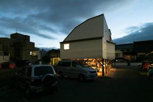 a small building with cars parked in a parking lot at Social Guest House neltoko in Nanao