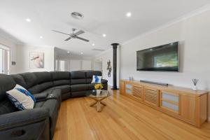 een woonkamer met een zwarte bank en een flatscreen-tv bij Kookaburra Heights in Mollymook