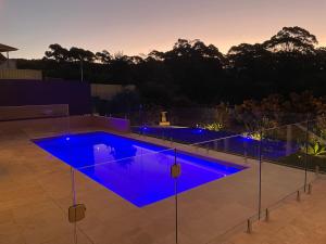 een zwembad met blauwe verlichting in de achtertuin bij Kookaburra Heights in Mollymook