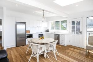 a kitchen with white cabinets and a table and chairs at Pas Beach House Apartment 1 in Mollymook