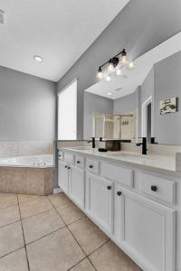 a large bathroom with white cabinets and a tub at Magical Retreat in Kissimmee