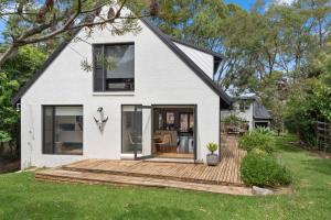 a white house with a wooden deck in the yard at The Hideaway at Manyana in Manyana