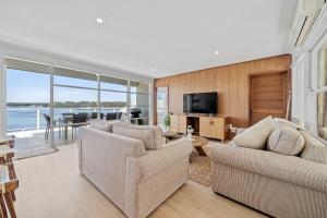 a living room with two couches and a television at Burrill Lake Cottage in Burrill Lake