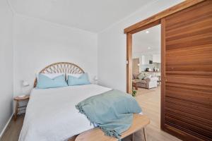 a bedroom with a bed with blue pillows on it at Burrill Lake Cottage in Burrill Lake