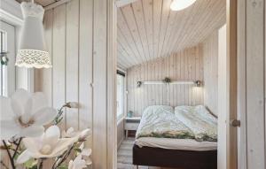 una camera con un letto in una stanza con pareti in legno di 2 Bedroom Amazing Home In Sby a Sæby