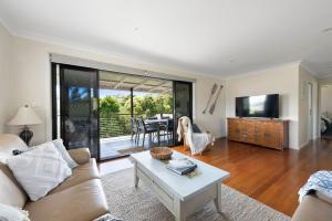 sala de estar con sofá y mesa en Barefoot Beach House Narrawallee, en Narrawallee