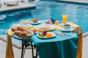 een tafel met ontbijtproducten naast een zwembad bij Galápagos Isabela Hotel Loja in Puerto Villamil