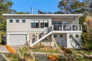 a white house with a porch and a balcony at Breezeway Mollymook in Mollymook