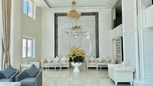 a living room with white furniture and a chandelier at Le Marais Hotel Dalat in Da Lat