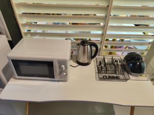 a microwave sitting on a white counter with a shelf at Met A Space Pod @Phrom Phong in Bangkok