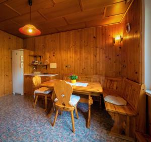 eine Küche mit einem Holztisch und Stühlen sowie einem Kühlschrank in der Unterkunft Kiara rooms in Jesenice
