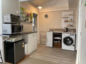 a kitchen with a washing machine and a microwave at Mill Corner Studios in Matamata