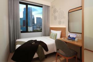 a hotel room with a bed and a desk and a window at Citadines Gatot Subroto Jakarta in Jakarta