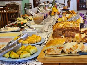 a long table filled with different types of bread and pastries at Pousada Monte Silvestre in Monte Verde