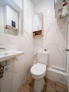 a white bathroom with a toilet and a sink at Appartement tout équipé au coeur du Panier Vieux Port in Marseille