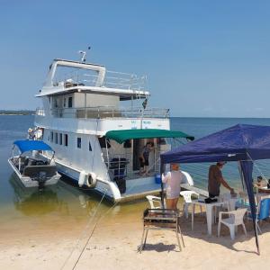 a boat parked on the beach with people sitting at a table at Barco Seu Meschede in Santarém