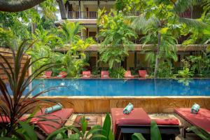 um resort com uma piscina e mesas e cadeiras vermelhas em Pandora Suite D'Angkor em Siem Reap