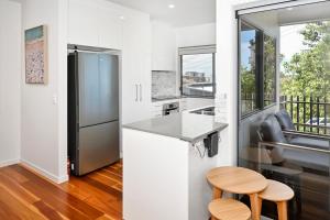 a kitchen with a stainless steel refrigerator and two stools at Spacious New 2 bedroom Kings Beach Townhouse ZF2 in Caloundra