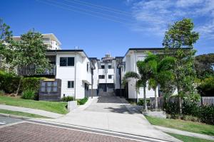 a street view of a white apartment building at Spacious New 2 bedroom Kings Beach Townhouse ZF2 in Caloundra