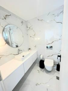 a white bathroom with a sink and a mirror at Oceana Suites in Georgioupolis