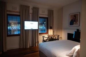 a bedroom with a bed and a flat screen tv at Warders Hotel Fremantle Markets in Fremantle