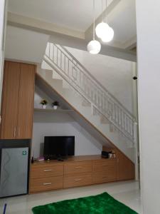 uma sala de estar com uma escada e uma televisão em Villa keluarga sejahtera em Batu