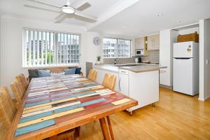 a kitchen and dining room with a wooden table with chairs at Stylish 2 B/R Kings Beach Apartment (6 guests) ZF4 in Caloundra