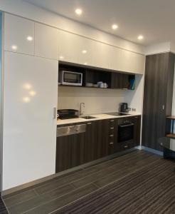 Modern, Quiet 1 Bed Apt on Fitzroy St, Opposite Albert Park في ملبورن: مطبخ مع دواليب بيضاء وميكرويف