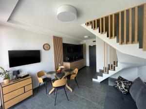 ein Wohnzimmer mit einem Tisch, Stühlen und einer Treppe in der Unterkunft Apartament BALTIC 1 in Jastrzębia Góra