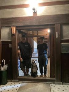 dwóch mężczyzn i pies stojący przed lustrem w obiekcie Old Japanese House w mieście Tondabayashi