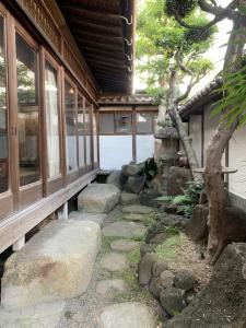 un jardin avec des rochers et un arbre en face d'un bâtiment dans l'établissement Old Japanese House, à Tondabayashi