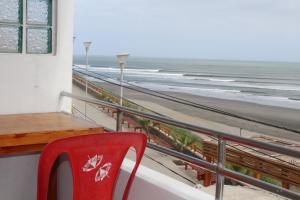 une chaise rouge assise sur un balcon donnant sur la plage dans l'établissement TITI SURF CHICAMA, à Puerto Chicama