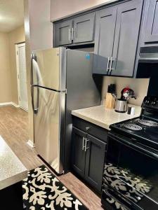 una cocina con nevera de acero inoxidable y armarios negros en Summer Getaway in Fondren! Sleeps 6 with pool Access! en Jackson