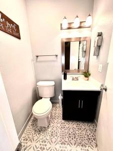 a white bathroom with a toilet and a sink at Cozy Fondren Getaway-Short walk to coffee shops, hospital, and restaurants! in Jackson