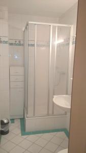 ein weißes Bad mit einer Dusche und einem Waschbecken in der Unterkunft Leichtmatrose in Dorum Neufeld